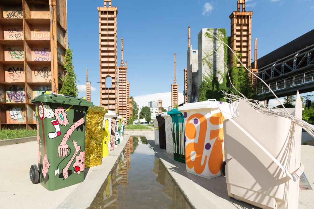 Painted bins lined along a reflecting pool at an industrial site