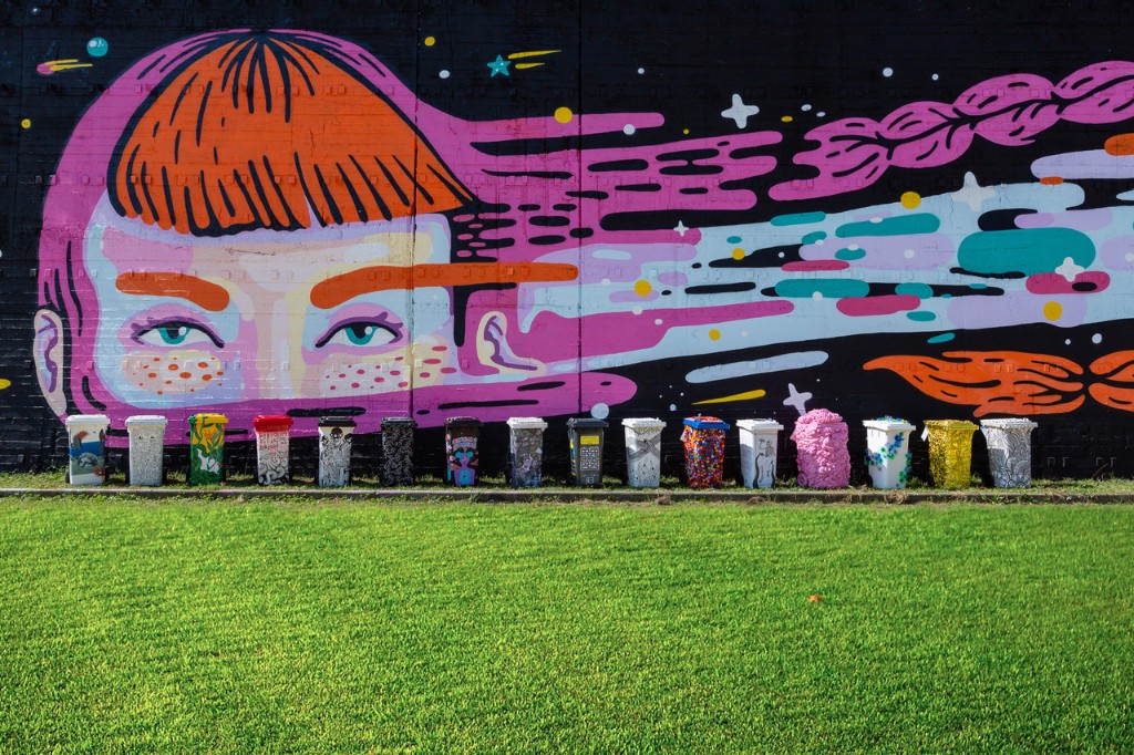 A row of painted bins beneath a large mural